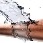 Water splashing from a copper pipe, illustrating plumbing emergencies and water dynamics, from Lodder Brothers Limited.