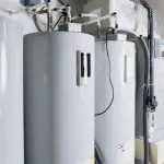 Two gray water heaters with pipes in a plumbing setting by Charles Krull & Son, Inc.