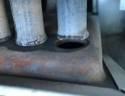 Cracked heat exchanger in a furnace, indicating potential gas accumulation and delayed ignition issues, relevant to furnace maintenance concerns.