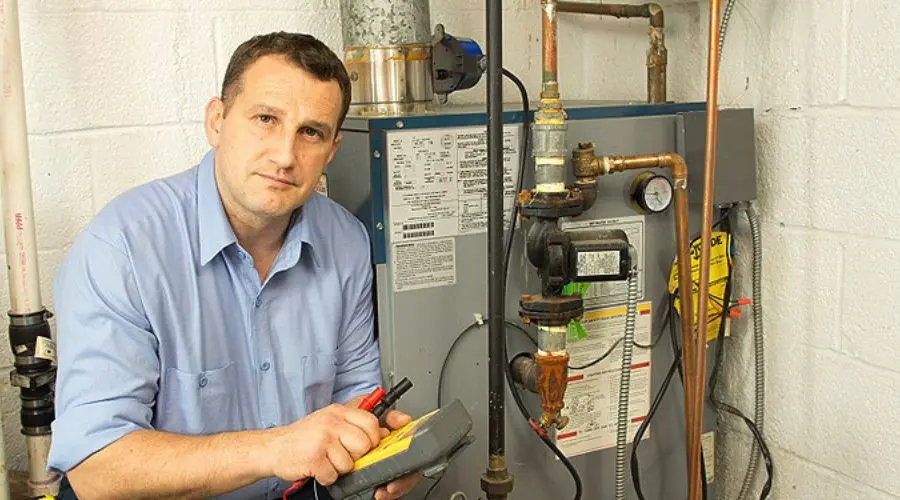 Man inspecting a water heater system with a multimeter, emphasizing professional heater maintenance and repair services.