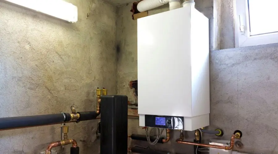Tankless water heater mounted on a wall in a plumbing setup, showcasing pipes and connections in a residential setting, relevant to plumbing service upgrades.