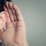 Close-up of a human hand cupping an ear, illustrating attentiveness to plumbing service advice from Charles Krull & Son, Inc.