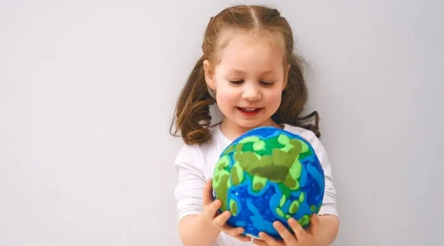 Young girl exploring a colorful globe, representing global understanding in plumbing and heating services.