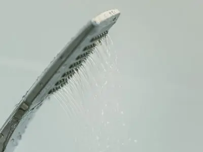 Showerhead with water flowing, illustrating potential signs of leaks in plumbing systems.
