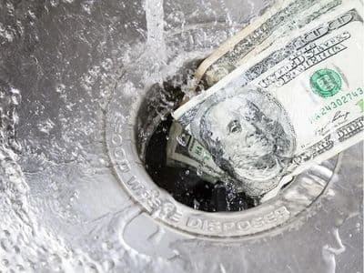 Dollars being washed down a sink drain, symbolizing wasted money due to plumbing issues like leaks affecting water bills.
