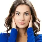 Young woman with brown hair in a blue top covering ears, concerned about water heater noises. Charles Krull & Son plumbing.