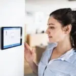 Young woman engaging with a digital screen showing HVAC data, illustrating thermostat maintenance and troubleshooting tips.