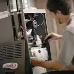 Technician performing routine maintenance on a Lennox furnace, demonstrating HVAC expertise for home heating systems.