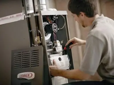 Technician performing maintenance on a Lennox heating system, emphasizing the importance of regular care for optimal performance and longevity.