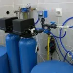 Blue cylindrical tanks and control panel in a water filtration system by Charles Krull & Son, Inc. plumbing services.