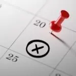 Close-up of a calendar page with a red pushpin marking the 20th, highlighting important home maintenance plan reminders.