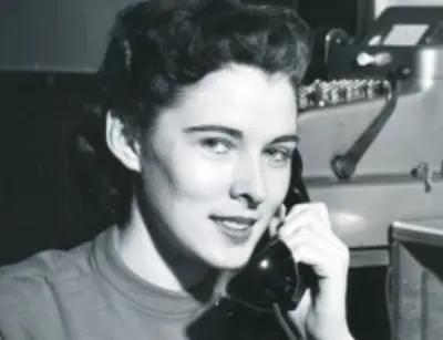 Lillian Baumbach, the first female master plumber, smiling while on the phone, symbolizing her groundbreaking achievements in the plumbing industry.