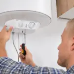 Plumber servicing a wall-mounted water heater with tools, emphasizing boiler maintenance by Charles Krull & Son, Inc.