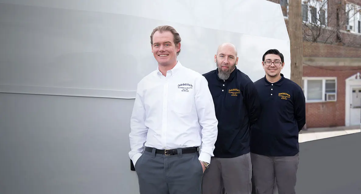 Three professionals from Charles Krull & Son, Inc. Plumbing & Heating, smiling and standing together, showcasing their commitment to quality plumbing and heating services.