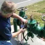 Man adjusting a green water meter for certified backflow testing by Charles Krull & Son, Inc. Plumbing & Heating.