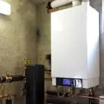 White boiler unit with digital display and pipes in industrial setting by Charles Krull & Son, Inc. Plumbing & Heating.