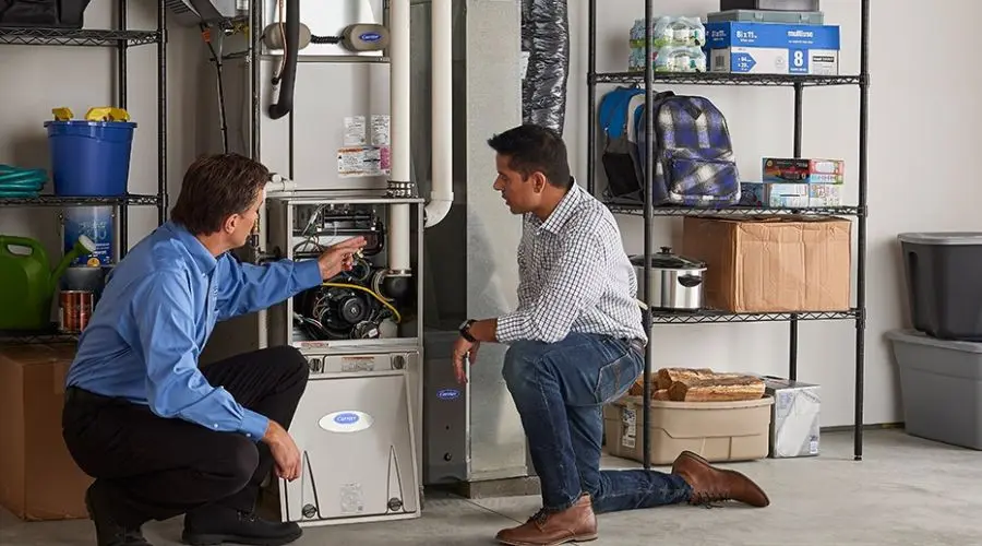 Technician and client inspecting a home heating system in a garage, emphasizing expert advice on heater repairs and maintenance.