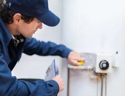 Technician inspecting a residential boiler's control panel and settings, highlighting boiler maintenance for homeowners.
