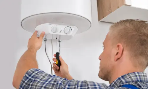 Technician performing boiler maintenance with a screwdriver, ensuring proper functionality for winter heating.