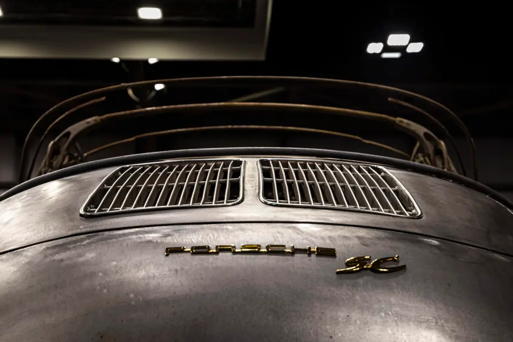 Aces Auto Elite - Low-angle view of the rear of a vintage Porsche car, highlighting metallic paint, ventilation grilles, and gold Porsche 2C lettering. The soft indoor lighting showcases meticulous restoration and preservation of classic details. | Arizona Luxury & Exotic Car Service