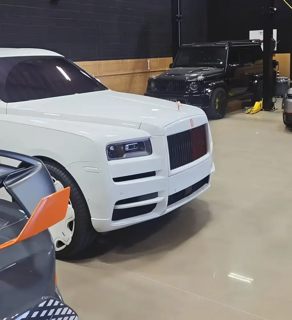 Aces Auto Elite - A white Rolls-Royce, a black SUV, and part of a sports car are parked indoors on a polished concrete floor in a garage with black and tan walls. | Arizona Luxury & Exotic Car Service