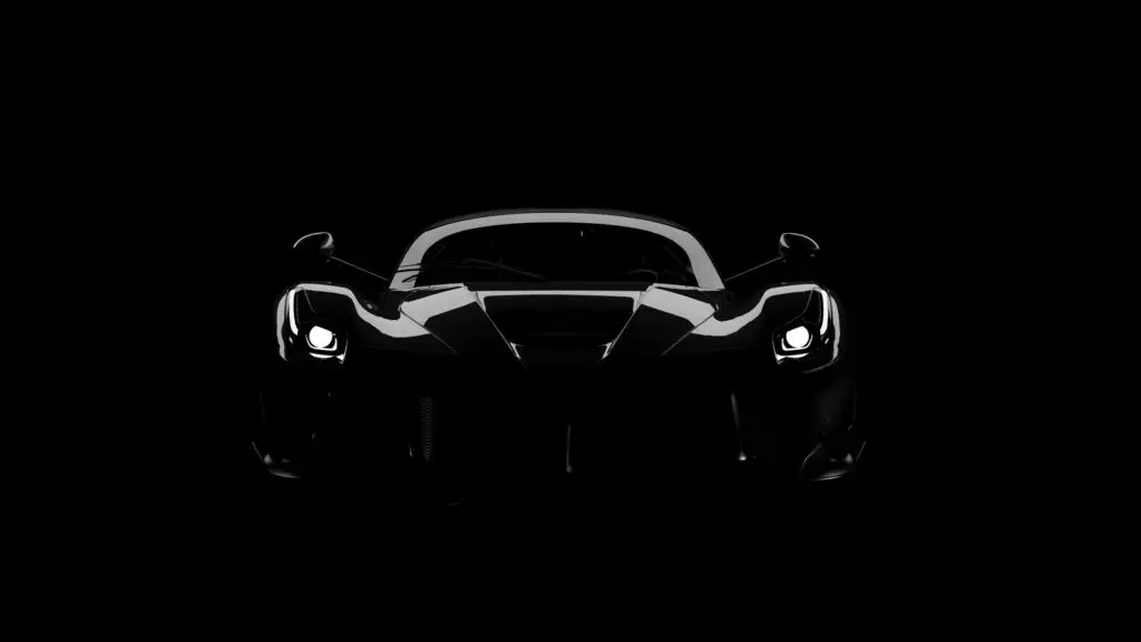 Aces Auto Elite - A sleek sports car is photographed head-on in low light, with only its headlights and body edges illuminated against a black background. | Arizona Luxury & Exotic Car Service