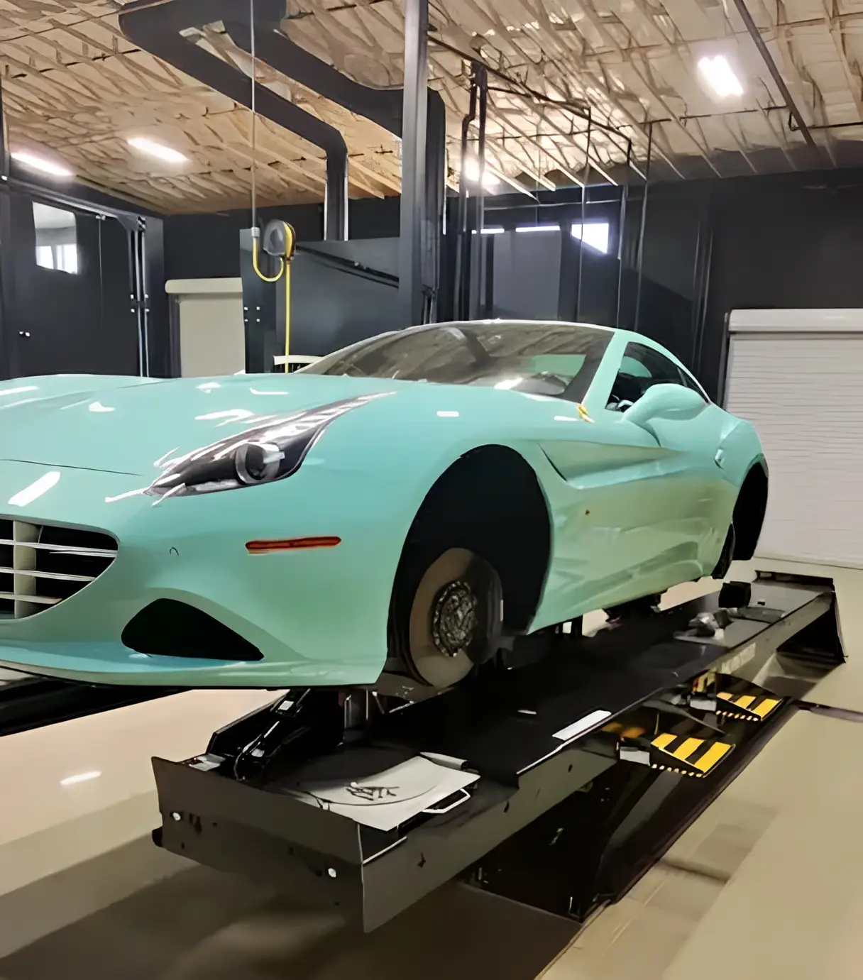 Aces Auto Elite - A light blue sports car without front wheels is elevated on a hydraulic lift inside a modern auto repair shop with bright lighting and exposed ceiling. | Arizona Luxury & Exotic Car Service