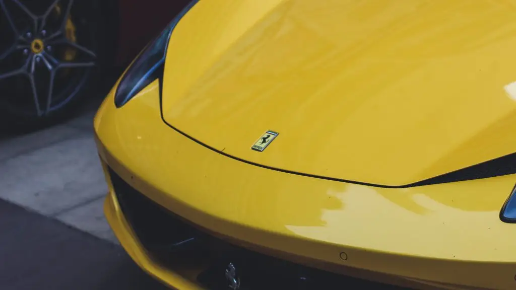 Aces Auto Elite - Close-up of the front hood of a yellow Ferrari sports car, featuring the Ferrari logo. Part of another car with a visible wheel is seen in the background—ideal for showcasing ADAS Diagnostics on high-performance vehicles. | Arizona Luxury & Exotic Car Service