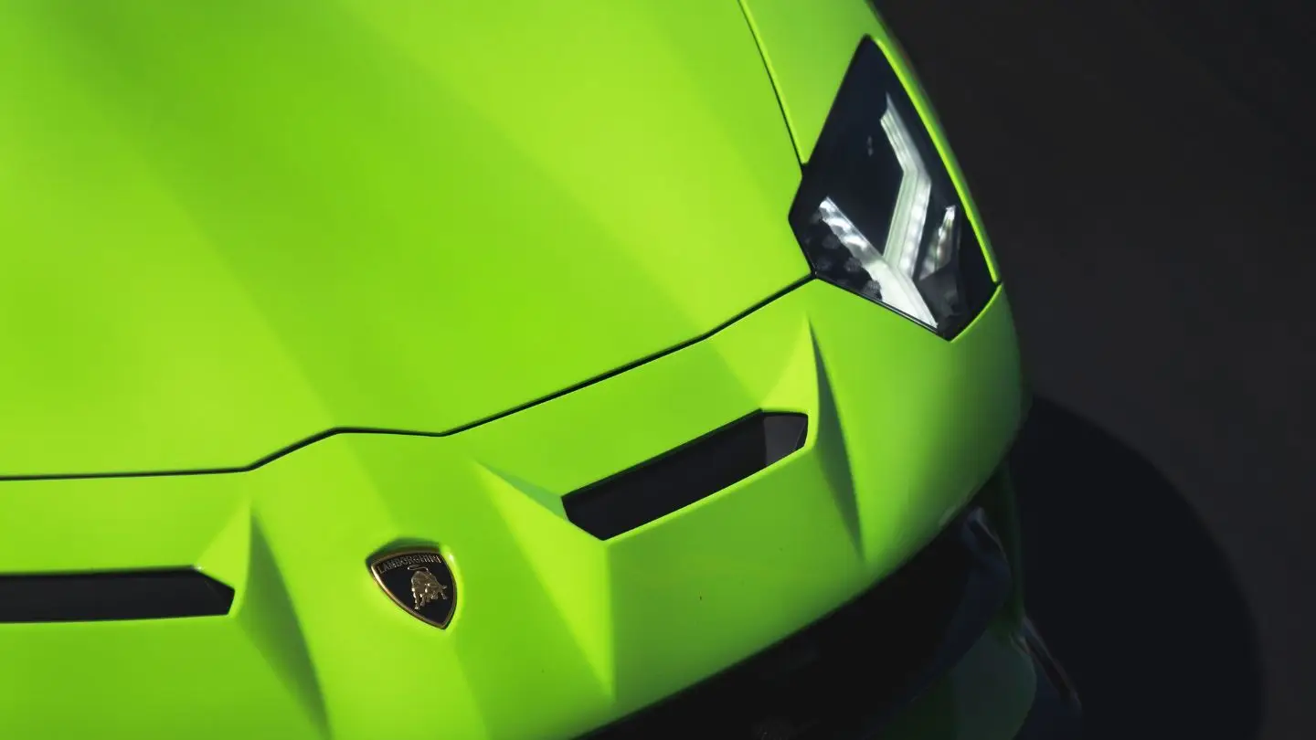 Aces Auto Elite - Close-up of the front end of a bright green Lamborghini, showing sharp lines, the emblem, and one angular LED headlight—a striking symbol of luxury often enjoyed through exclusive concierge services. | Arizona Luxury & Exotic Car Service