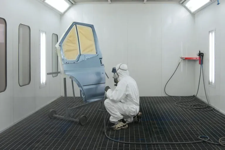 Technician replacing a damaged vehicle part during collision repair