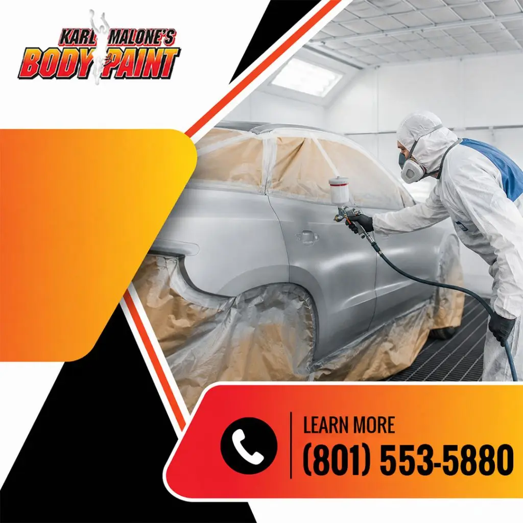 A technician wearing a full protective suit and respirator applying primer paint with a spray gun to a masked vehicle in a paint booth.