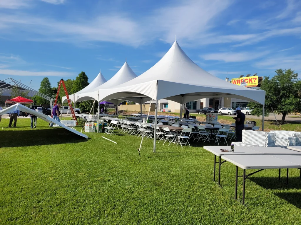 Large white party tents set up on green grass for an outdoor event in Kendall County, with tables and chairs arranged underneath, showcasing Affordable Party Tent Rentals' services.