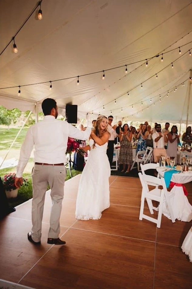 Wedding reception inside a large tent with dance floor and guests, Affordable Party Tent Rentals.