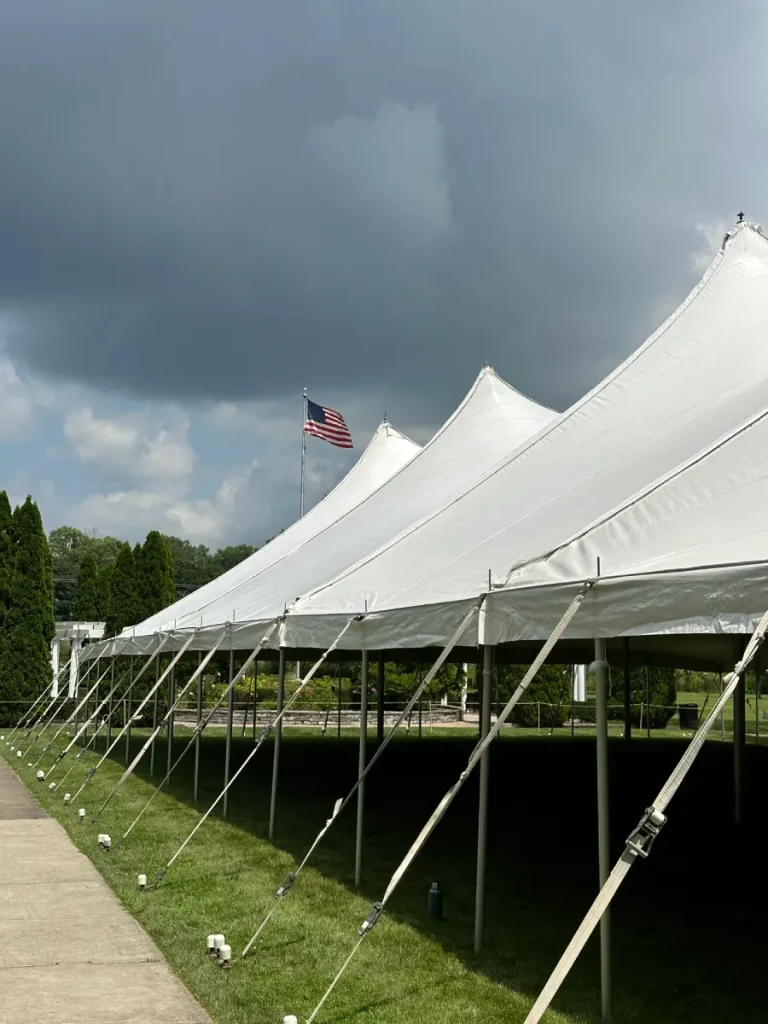 Large white event tent installed on a grassy outdoor venue beneath dark storm clouds