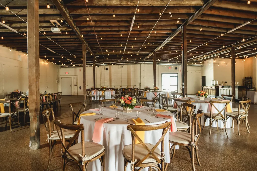 Wedding reception under a large white event tent with string lights, guest seating, and a wood dance floor