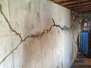 Bowing basement wall with a large horizontal crack showing structural damage caused by lateral soil pressure and foundation movement.