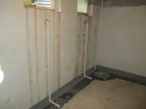 Basement drainage system and sump pump pit installed along a concrete block wall