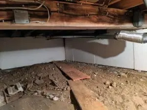 Crawl space interior showing dirt floor, wooden planks, and encapsulation materials, highlighting the importance of moisture prevention and structural integrity for home safety.