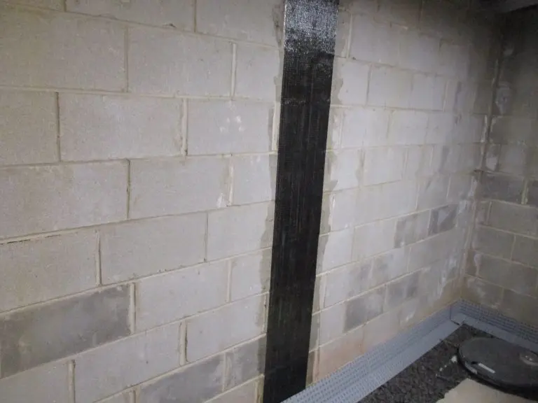 Carbon fiber reinforcement strip applied to a concrete basement wall, highlighting foundation repair techniques for structural integrity.