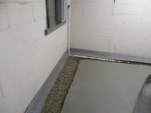 Interior French drain system installed along a basement perimeter to relieve hydrostatic pressure as part of an interior French drain vs exterior waterproofing solution.
