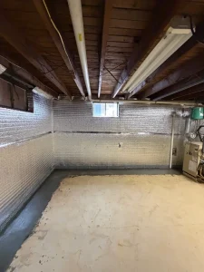 Completed basement waterproofing system in Lower Makefield Township, PA featuring insulated wall panels, an interior French drain, MiraDRI drainage membrane, and freshly poured concrete.
