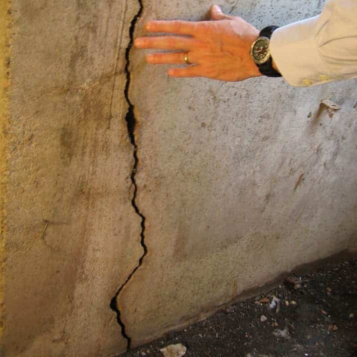 Large horizontal foundation crack with visible wall bowing in a basement, showing severe structural damage requiring immediate foundation repair.