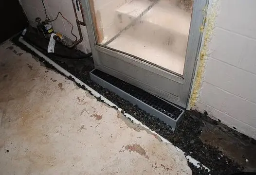 Interior drain tile system installed along a basement wall to stop floor seepage caused by hydrostatic pressure beneath the concrete slab.