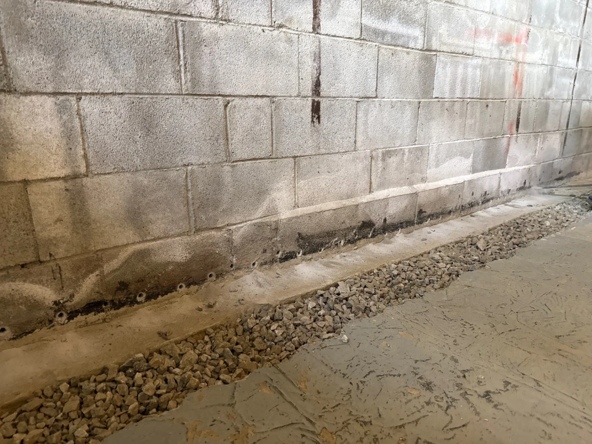 Interior basement waterproofing system installation with weep holes, drainage stone, and moisture control improvements in Patterson, NY.
