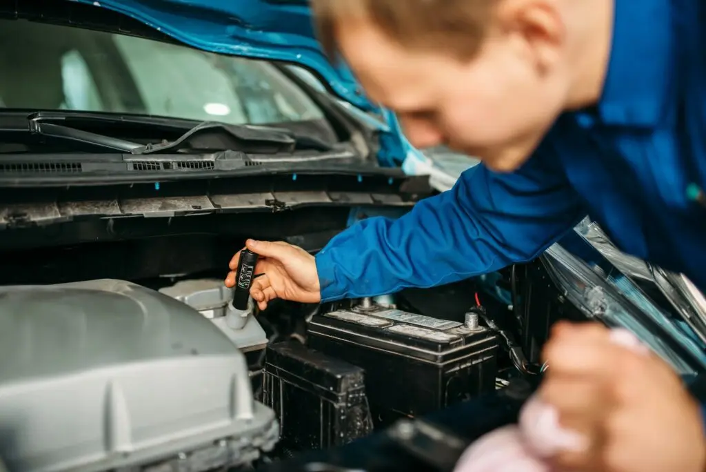 Male technician checks brake fluid level in car