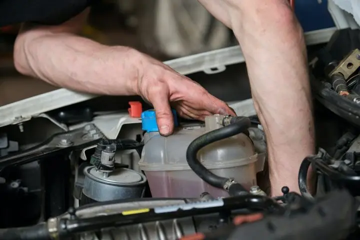 Car mechanic checking pulley on a car engine.