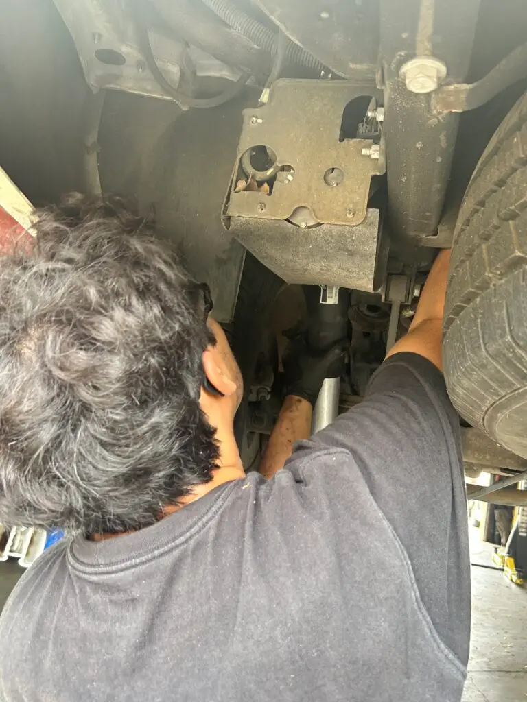 Technician replacing rear air suspension strut on Chevrolet Tahoe