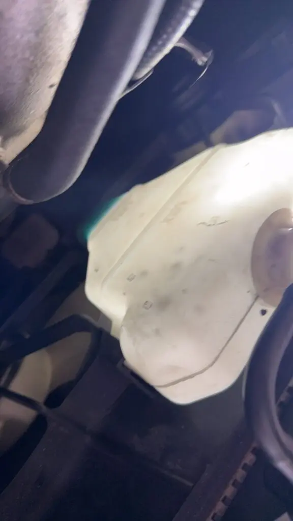 Low coolant level in the engine coolant reservoir indicating a possible coolant leak.