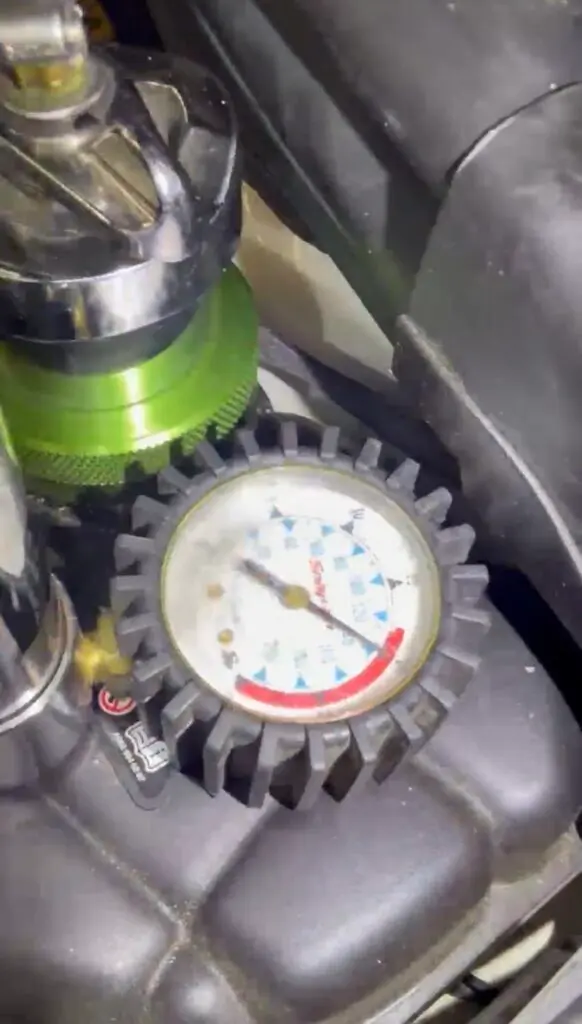 Technician performing a cooling system pressure test to diagnose a coolant leak.