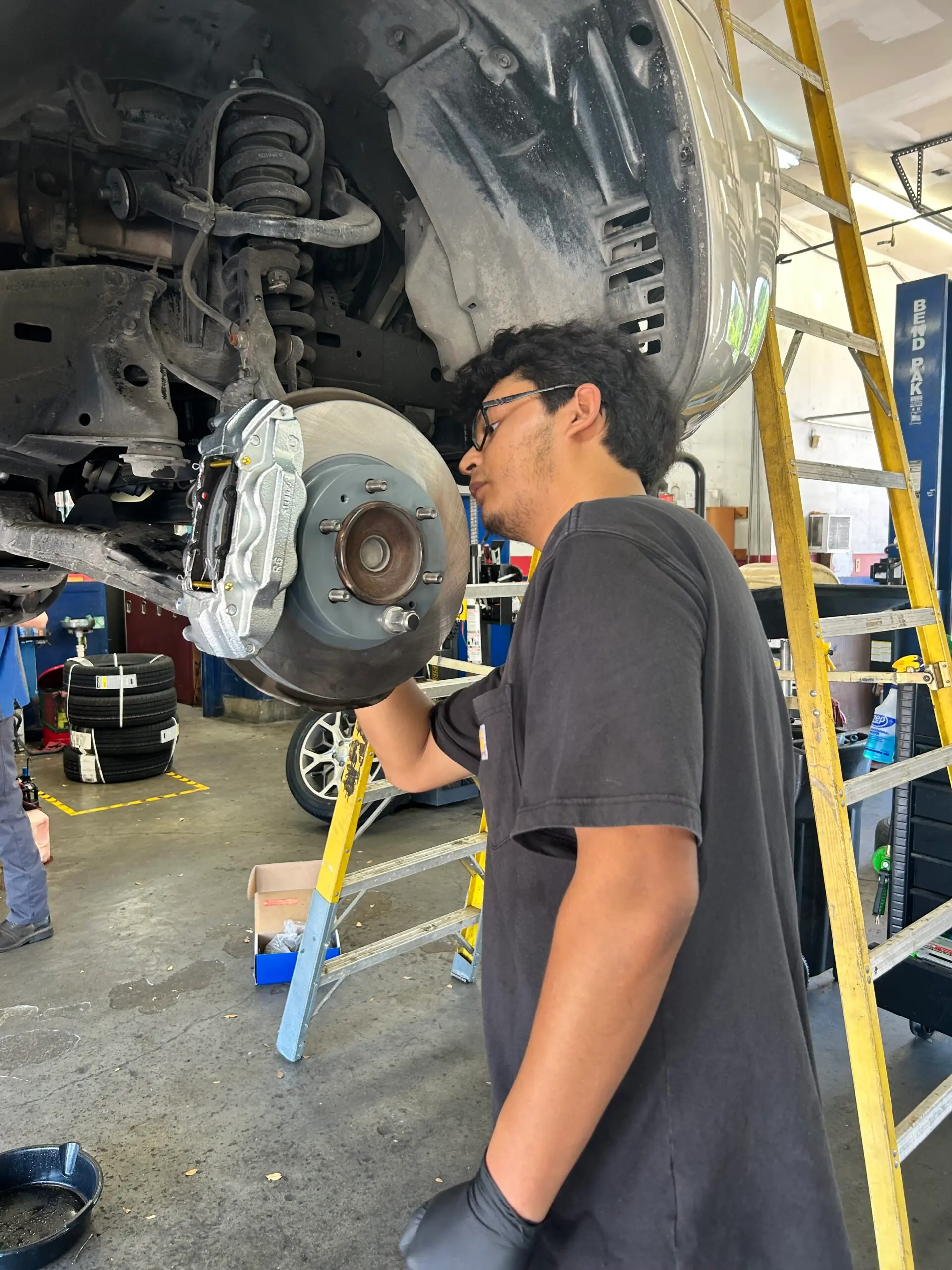 Technician installing new brake caliper and rotor on Toyota 4Runner in Houston